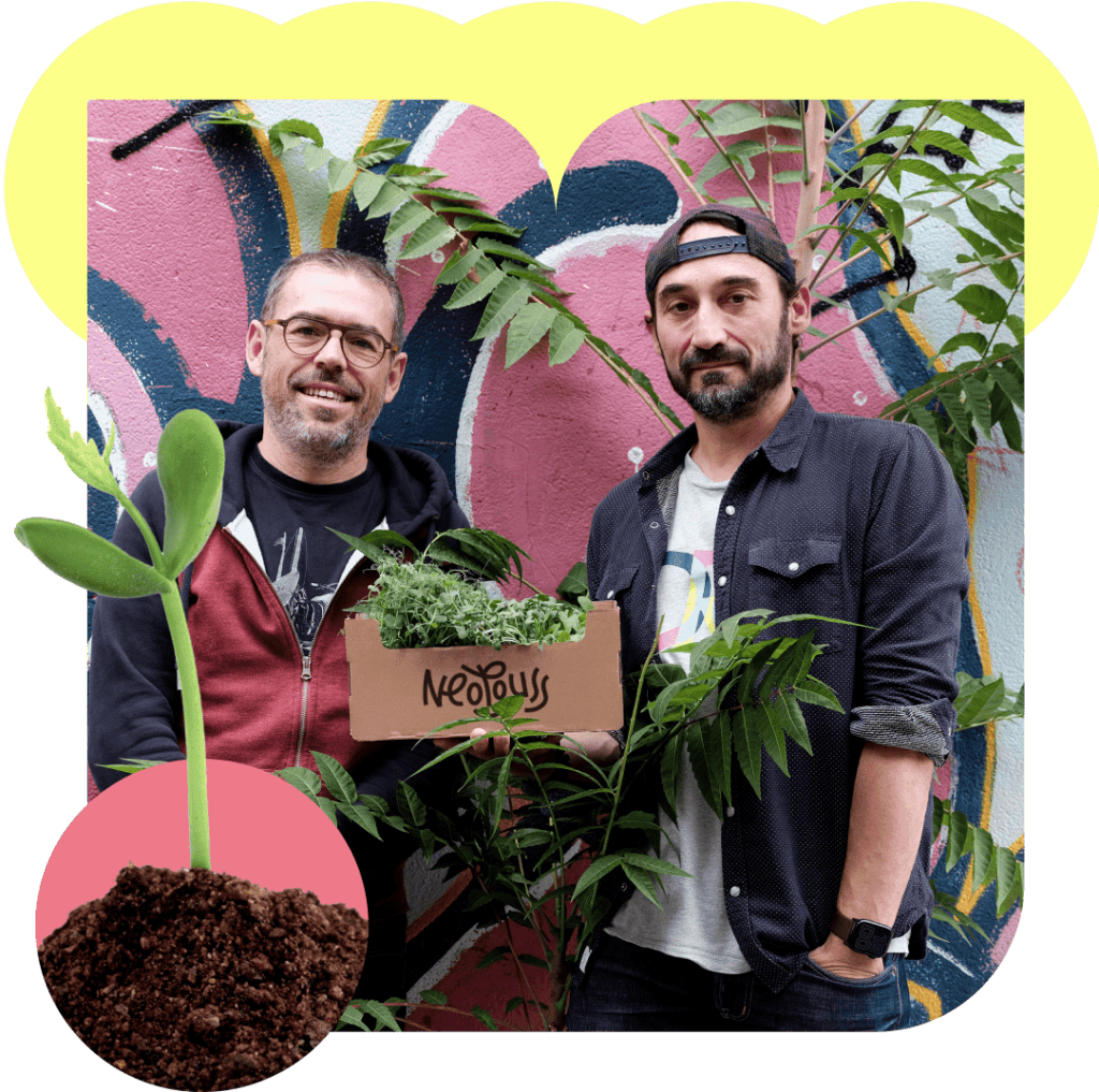 Deux hommes avec plantes et boîte de semis devant un mur graffité.